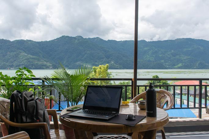 Marc working from a laptop setup by a lake in Nepal.